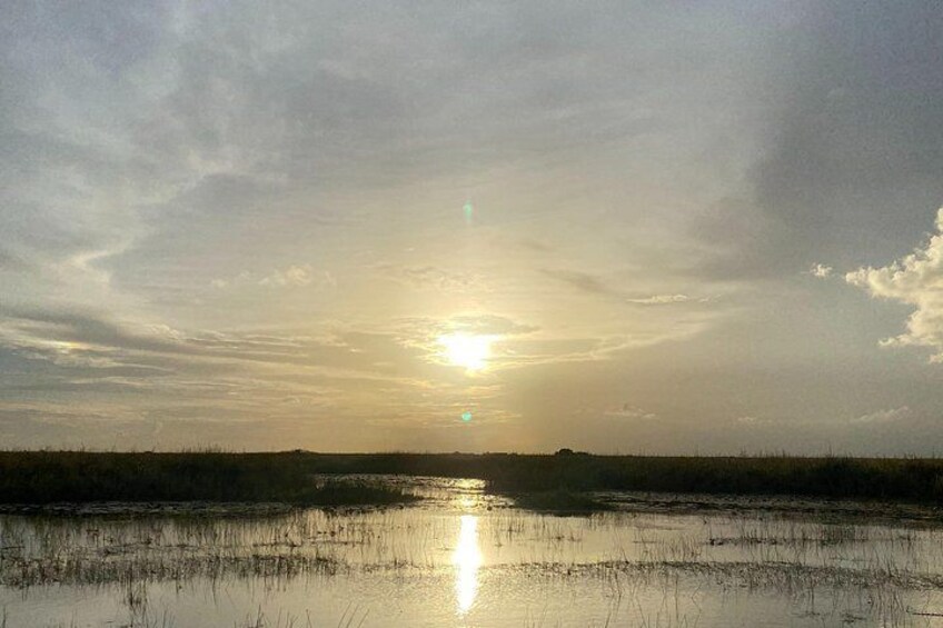 A sunset over a wetland landscape with a visible horizon line. 5