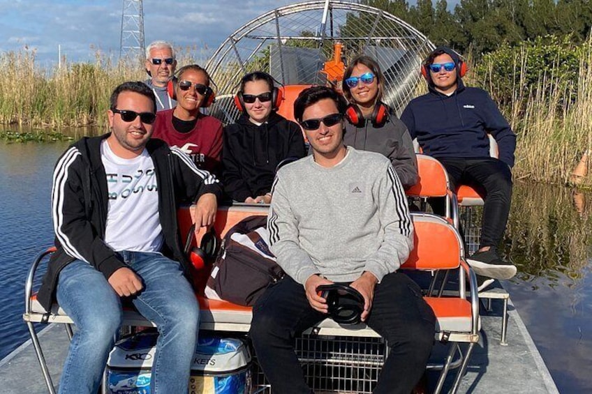A group of people on a boat with a metal structure overhead, surrounded by water and vegetation. 3