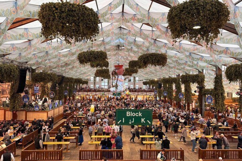 A crowded indoor market with wooden benches and hanging plants. 4