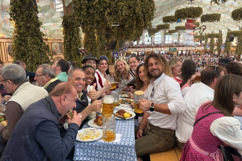 A group of people dining at an outdoor event with tables, food, and drinks. 3