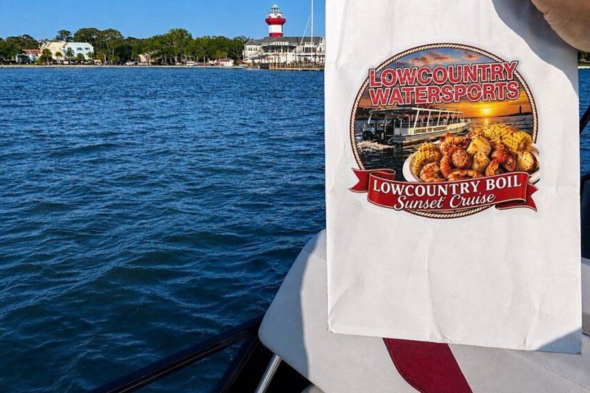 Et vandområde med et fyrtårn i baggrunden og en båd med en reklame-t-shirt, der viser en fiskeret. 3