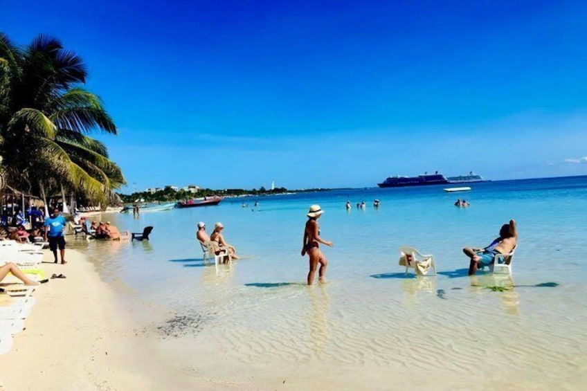 Una playa con gente tomando el sol, nadando y paseando por la orilla. 4
