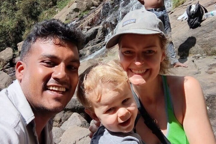 A family on a rocky trail with a waterfall in the background. 5