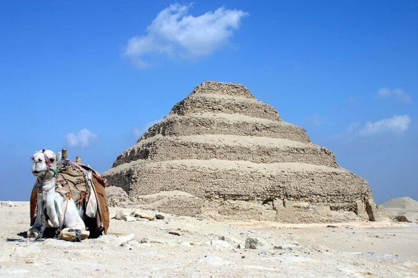 A pyramid structure in a desert landscape with a camel nearby. 2