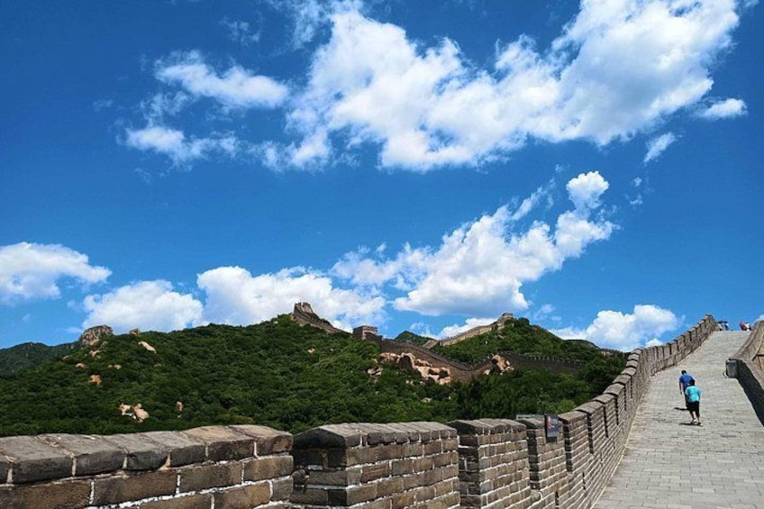 The Great Wall of China, a historic fortification, with a clear sky and lush greenery. 1