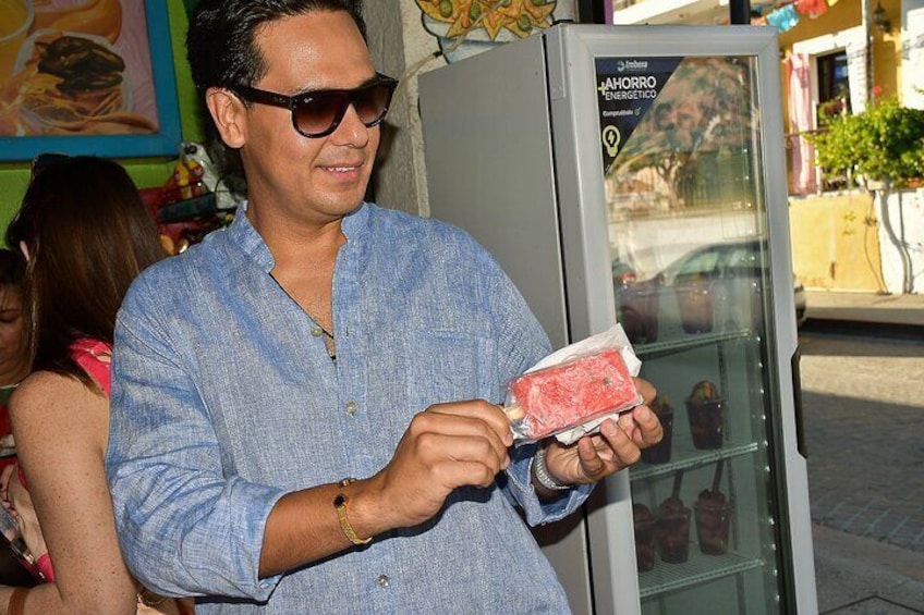 Un hombre sosteniendo un bocado de comida cerca de un refrigerador. 3