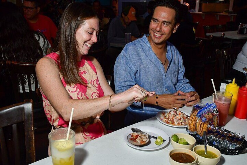 Dos personas cenando en un restaurante, con una mesa dispuesta con comida, bebidas y salsas. 1