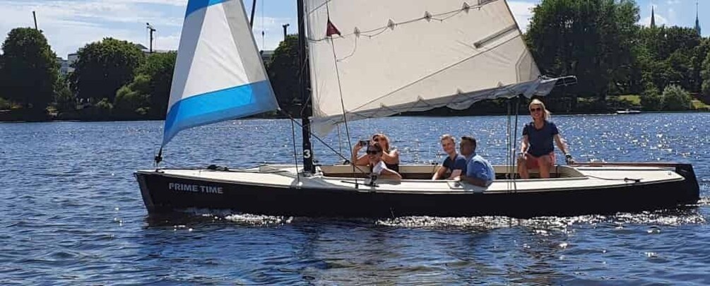 A sailboat named PRIME TIME on a body of water with people on board. 1