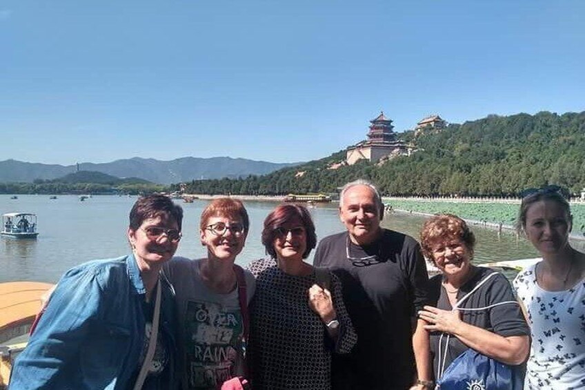 Un grupo de personas en un barco, con un paisaje montañoso y una pagoda al fondo. 5