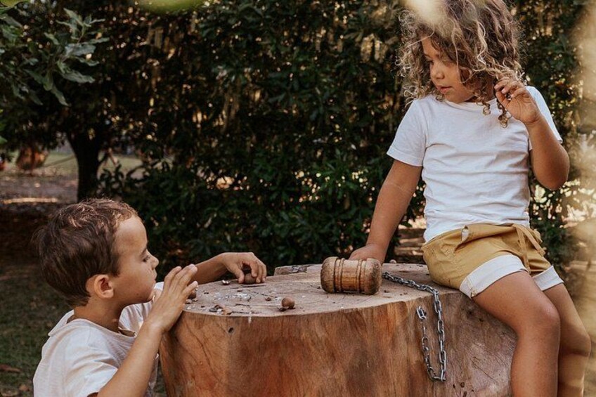 Two children sitting on a tree stump outdoors with greenery in the background. 2