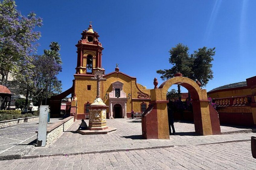 A historic church with a bell tower, a central archway, and a fountain. 5