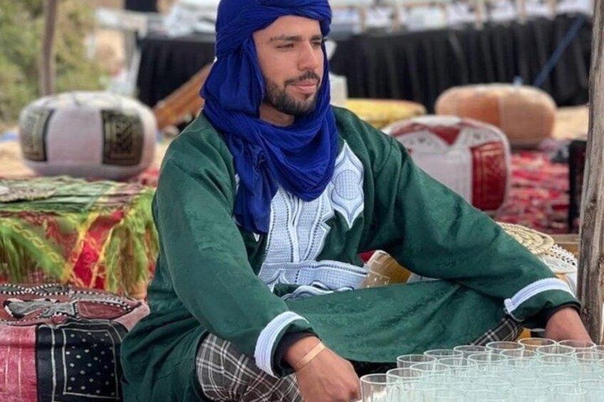 A person sitting at a market stall with various textiles and items. 2