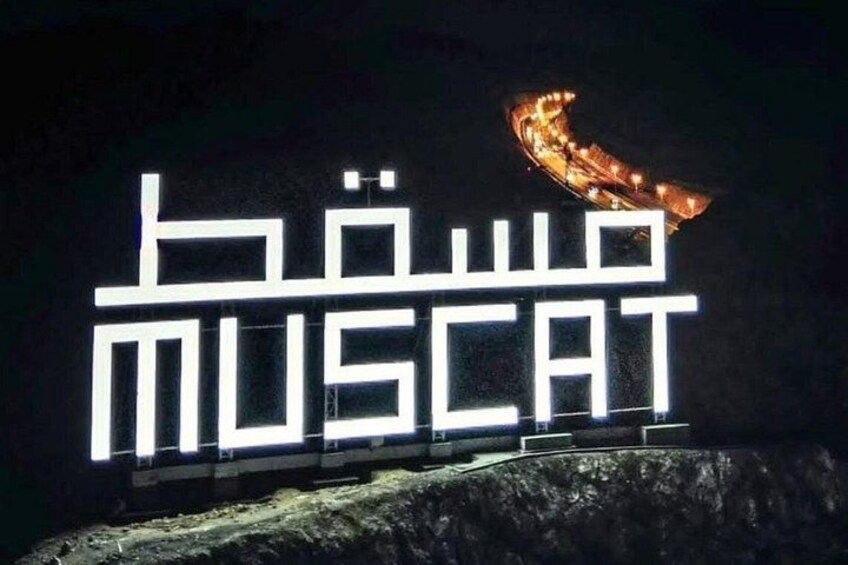 Illuminated text 'MUSCAT' on a dark background with a curved structure above. 5