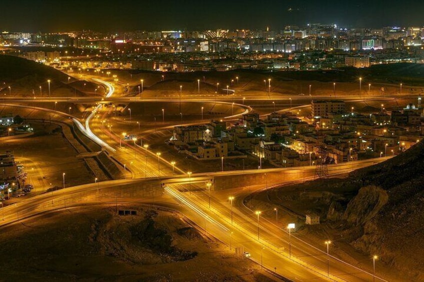 A nighttime aerial view of a city with illuminated highways and buildings. 4