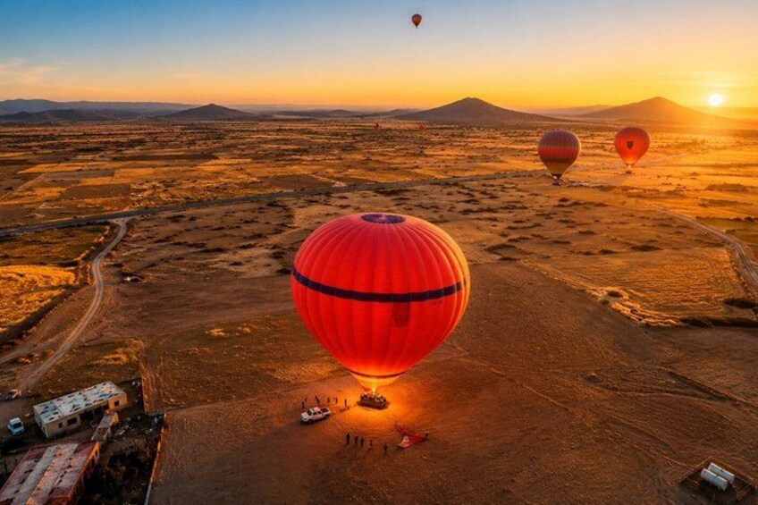 A desert landscape with hot air balloons and a dirt road. 3