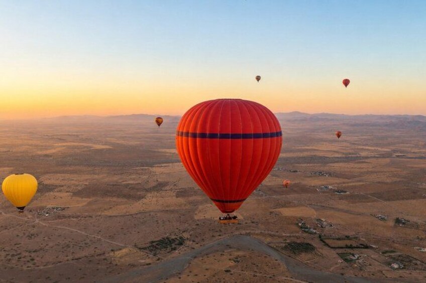 Hot air balloons over a desert landscape at sunset. 2