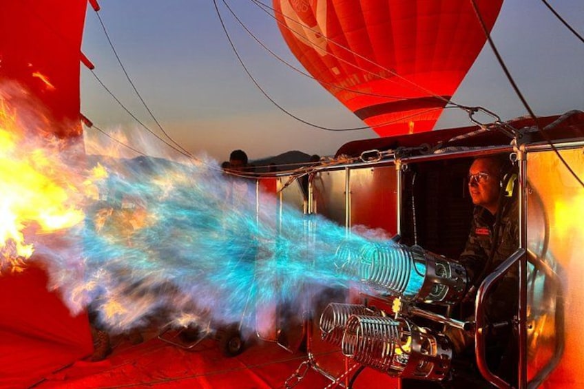 En varmluftsballon med en person i kurven, en stor rød ballon, og et køretøj med synlig motor. 2
