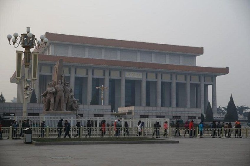 A large building with a red roof and a statue in front. 2