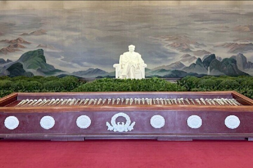 A traditional Chinese altar with a seated statue, surrounded by offerings, set against a mountainous landscape backdrop. 3