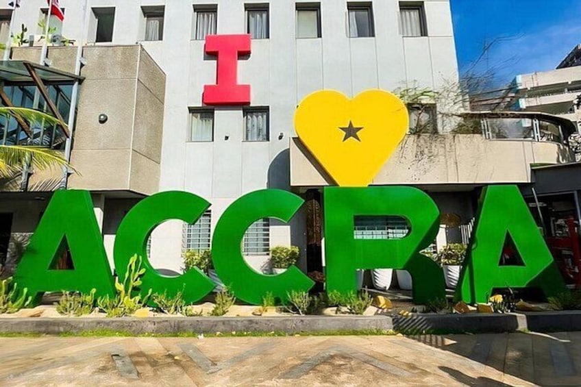 Un bâtiment sur lequel figurent en grandes lettres vertes l’inscription « ACCRA », avec un « I » rouge au-dessus, ainsi qu’un cœur jaune et un symbole en forme d’étoile. 1