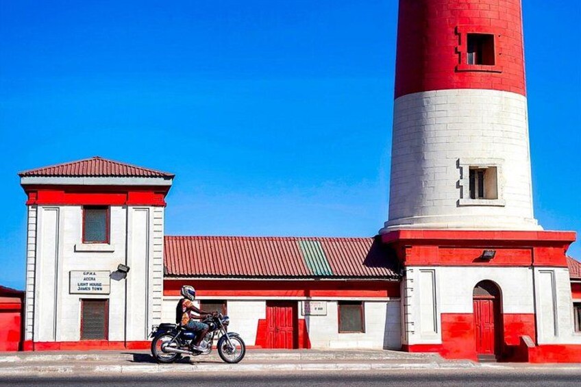 Un phare rouge et blanc, avec une personne à moto devant. 3