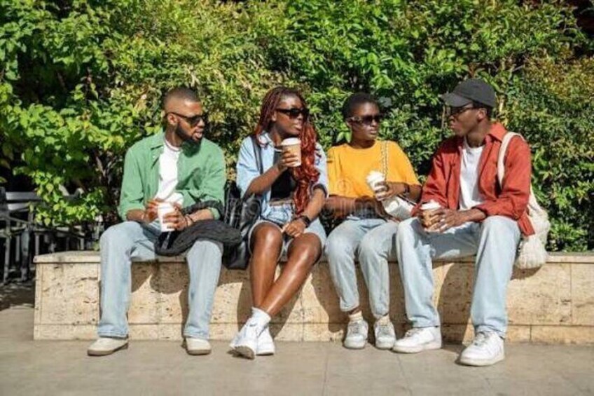 Four people sitting on a bench, holding coffee cups. 4