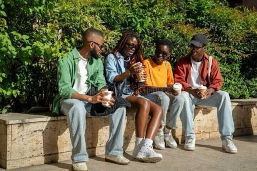 Four people sitting on a bench outdoors, each holding a cup. 5