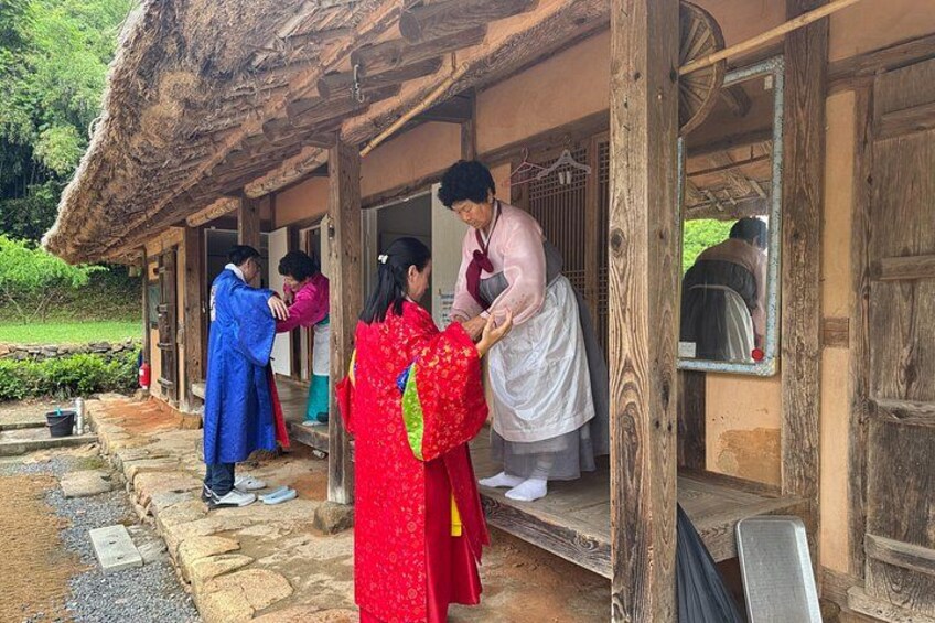 A traditional wooden building with a thatched roof, a stone pathway, and a wooden bench. 4