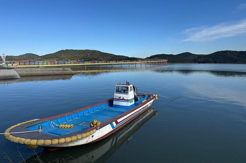 A boat docked at a pier with calm water and hills in the background. 3