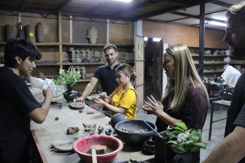A group of people in a workshop with pottery and plants. 3