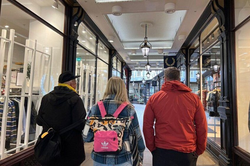 A corridor with storefronts on both sides, a person in a red jacket, and another in a black jacket. 2