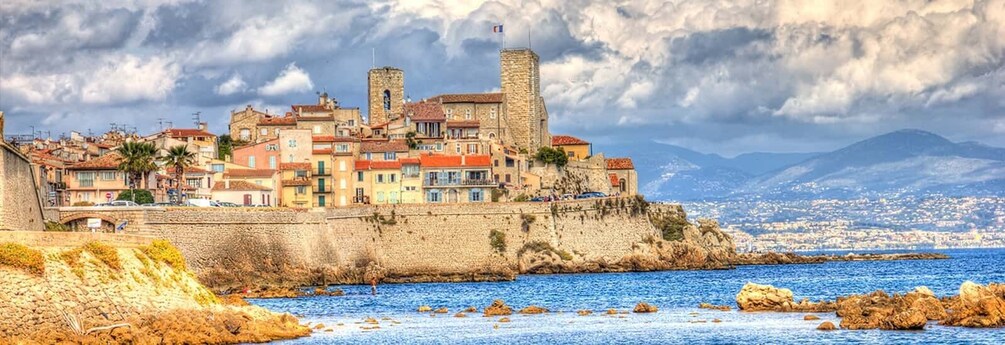 A coastal town with historic buildings, a prominent tower, and a rocky shoreline. 5