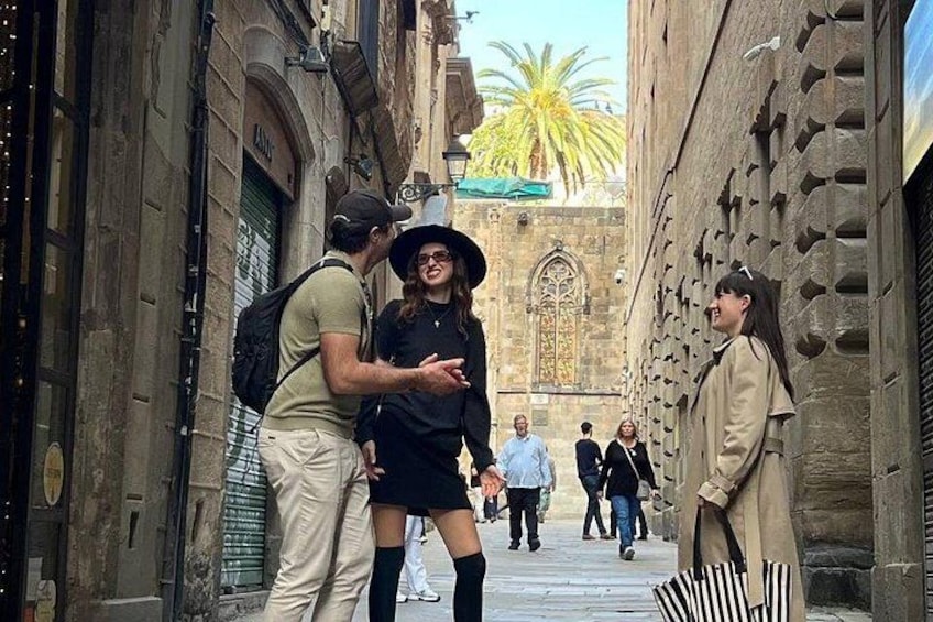 A narrow street with historic buildings, a palm tree, and people walking. 1