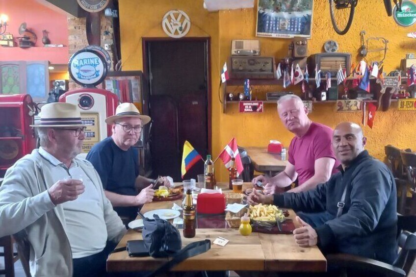 Four people sitting at a wooden table in a bar with various flags and memorabilia on the walls. 4