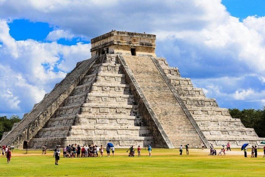 Un'imponente piramide con base ampia e pendio ripido, circondata da una zona erbosa dove passeggiano persone. 2