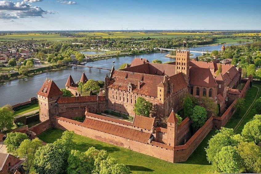 Un castillo histórico con múltiples torres, un río y vegetación circundante. 1
