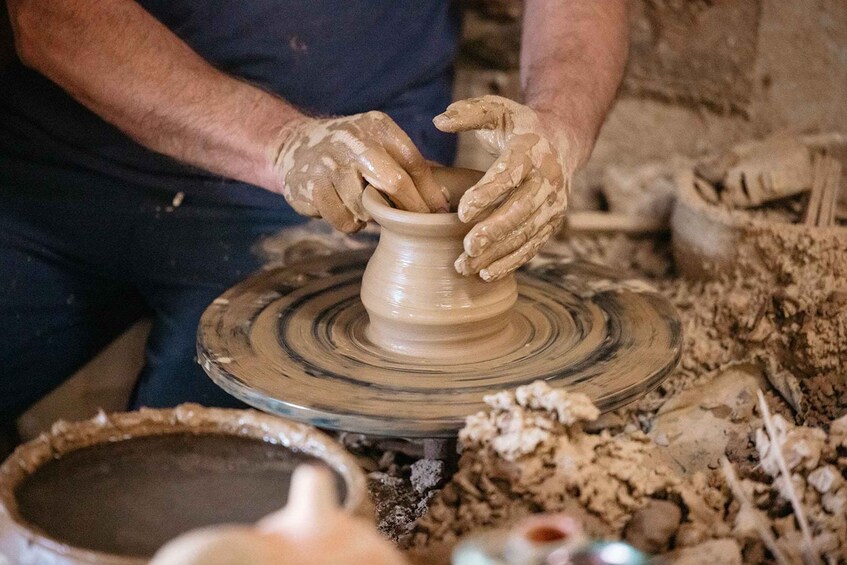 A person shaping a clay pot on a pottery wheel. 5