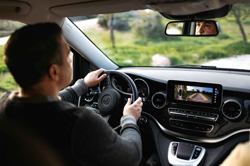 A person driving a car with a digital dashboard and a rearview mirror. 3