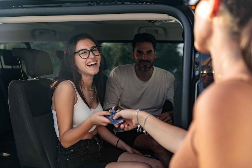 A person handing a card to another person inside a vehicle. 2