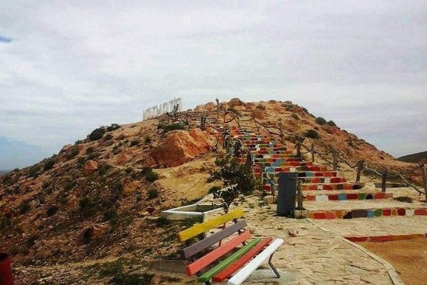 A hill with colorful steps leading up to a structure. 3