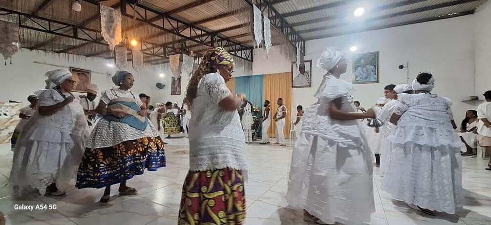 Un grupo de personas en una iglesia, algunas vestidas de blanco y otras con atuendos tradicionales coloridos. 3