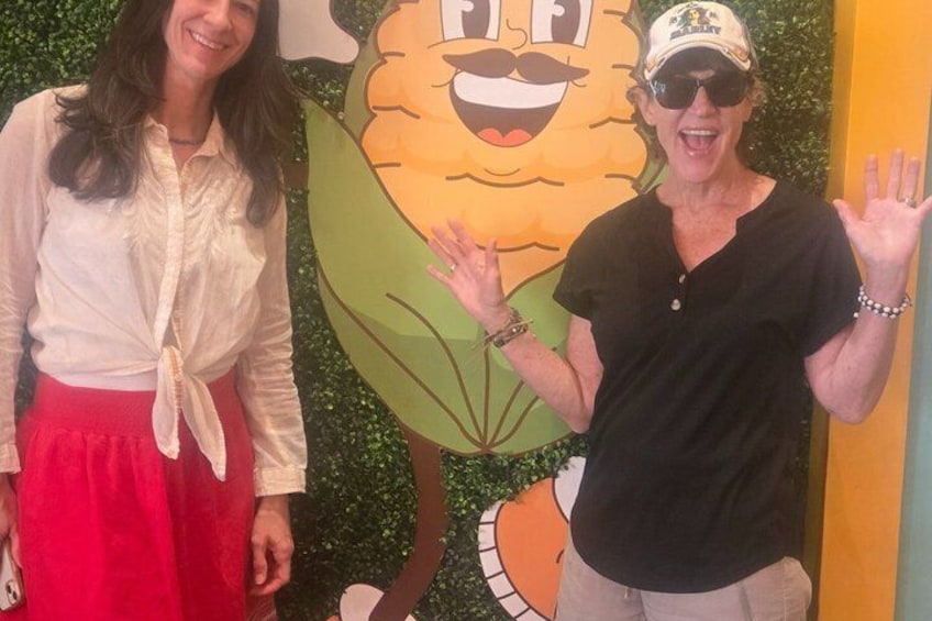 Two people standing in front of a cartoon character. 3