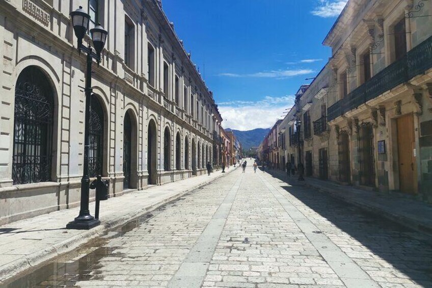 A cobblestone street lined with historic buildings, a lamppost, and a clear blue sky. 2