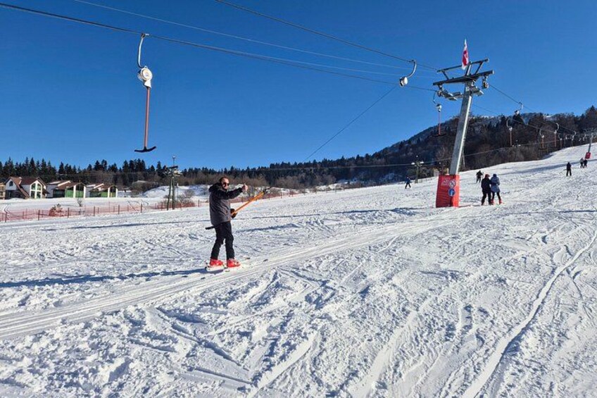 A snowy ski slope with a person on a snowboard, ski lift, and ski equipment. 5