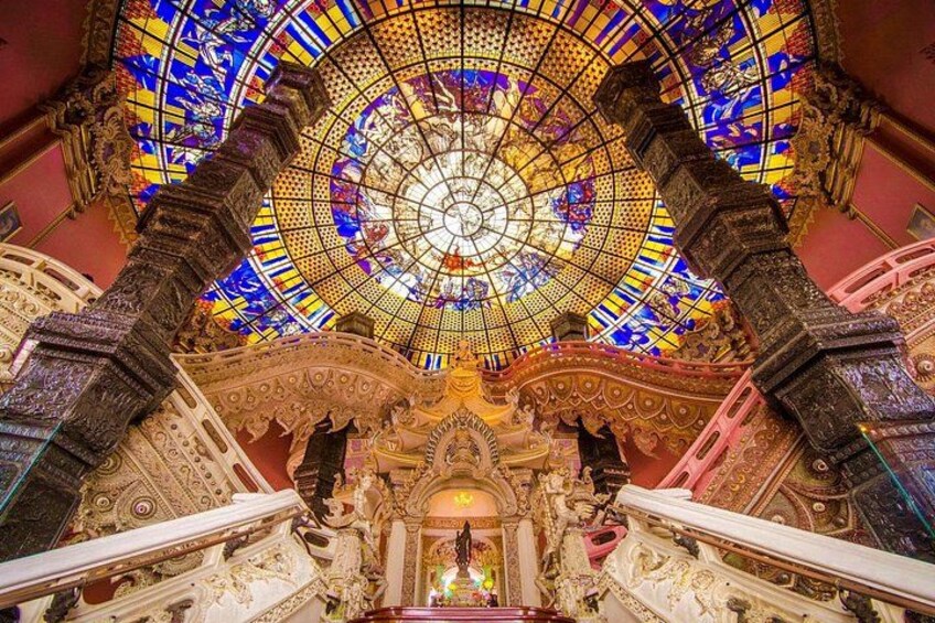 Ein prunkvolles Interieur mit einer großen Kuppel aus Buntglas, aufwendigen architektonischen Details und einer imposanten Treppe. 5