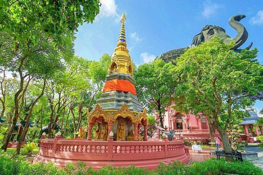 A temple with a golden spire, surrounded by lush greenery and a large elephant statue. 4