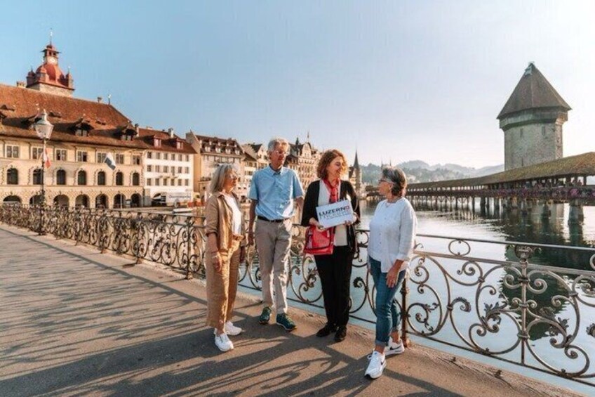 A group of people standing on a bridge with a river and historic buildings in the background. 4