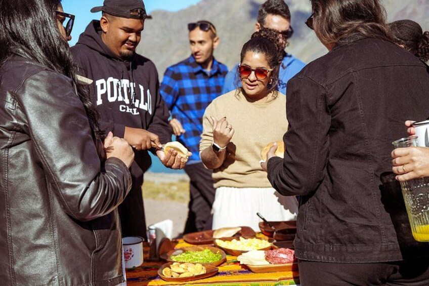 Un grupo de personas en un evento al aire libre, con una mesa de comida y bebidas. 2
