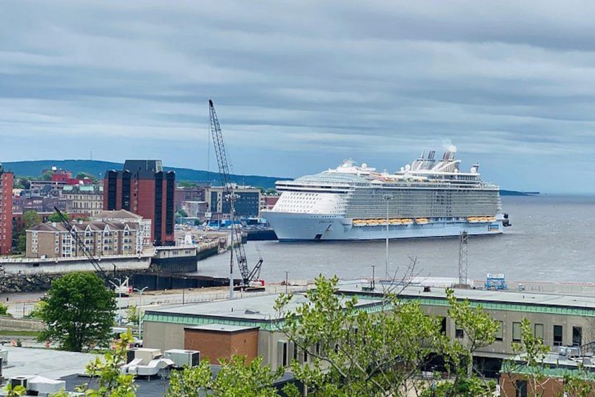 A large cruise ship docked at a port with cranes and buildings in the background. 2