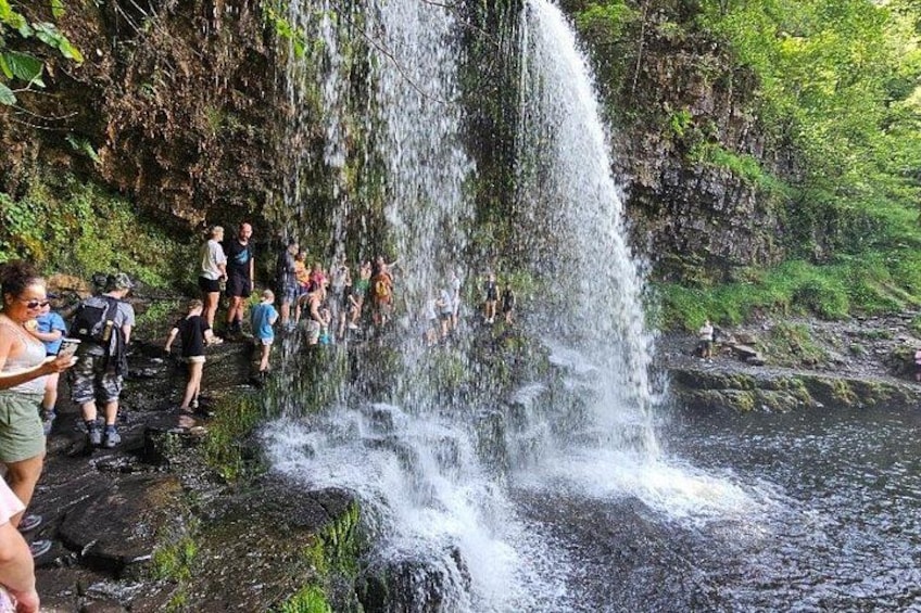 A waterfall with people standing on rocks and a river below. 2